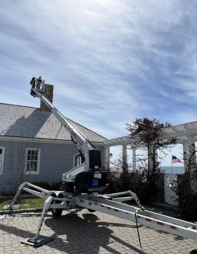 Technician using a lift to perform chimney repair on a home in Portland, ME.