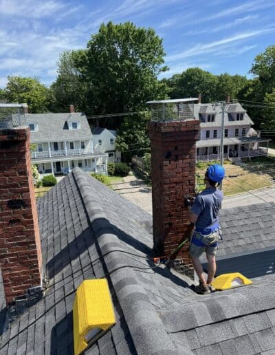 Technician repairing a brick chimney on a residential home in Portland, ME.