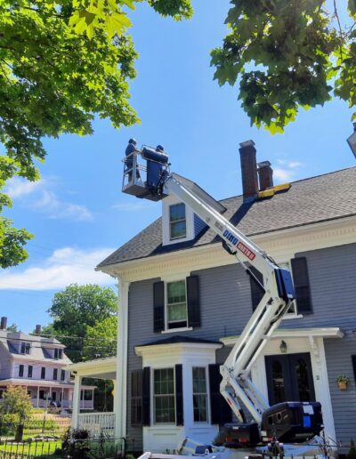 Crew using a lift to complete chimney masonry repair in Portland, ME.