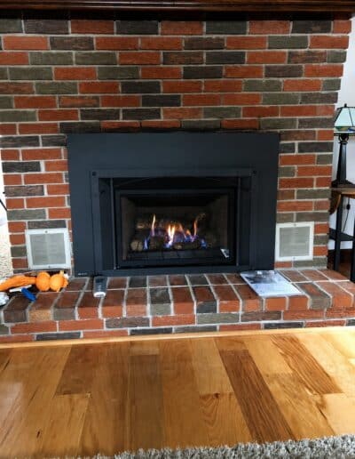 Gas fireplace insert installed in a red brick fireplace in Saco, ME by Frechette Chimney Sweeping.