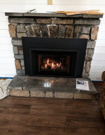 Gas fireplace insert installed in a stone fireplace surround in Sanford, ME by Frechette Chimney Sweeping.